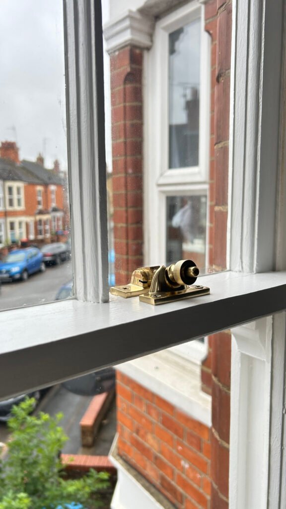 Victorian sash window with restored brass fastener in railway cottage, Wolverton near Milton Keynes